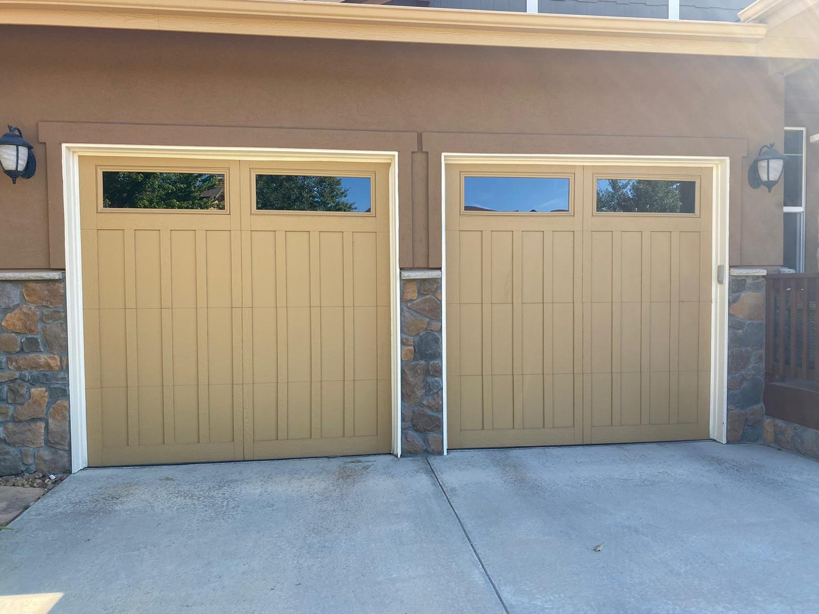 Two residential garage doors with upper windows and decorative panels